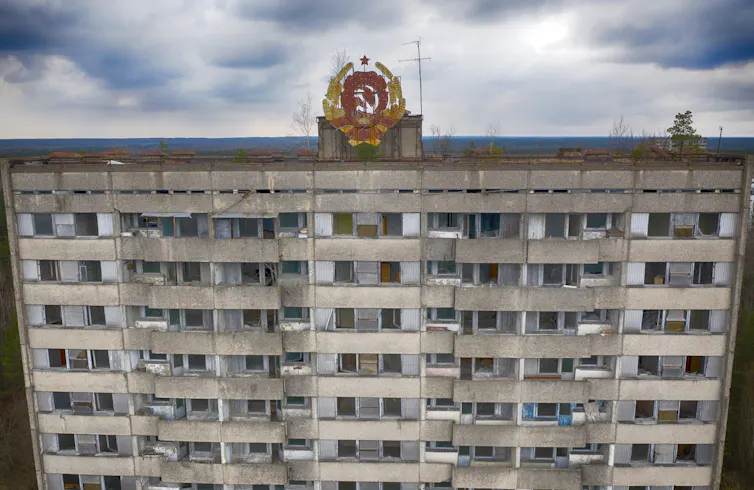 an abandoned multi-storey building with a soviet hammer andsickle emblem on the roof