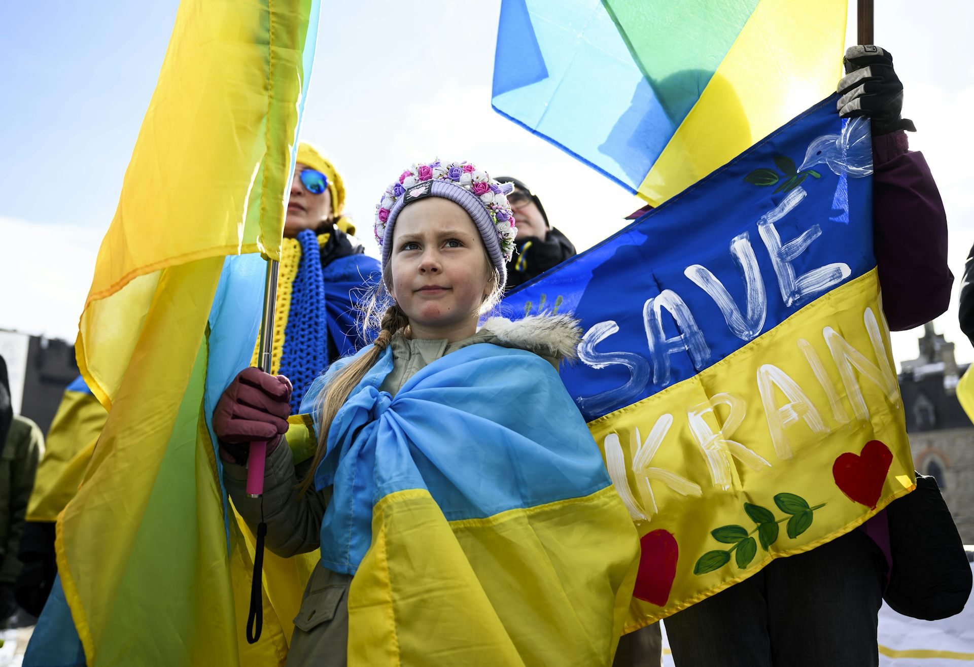 A young girl wrapped in a flag and holding another during a protest.
