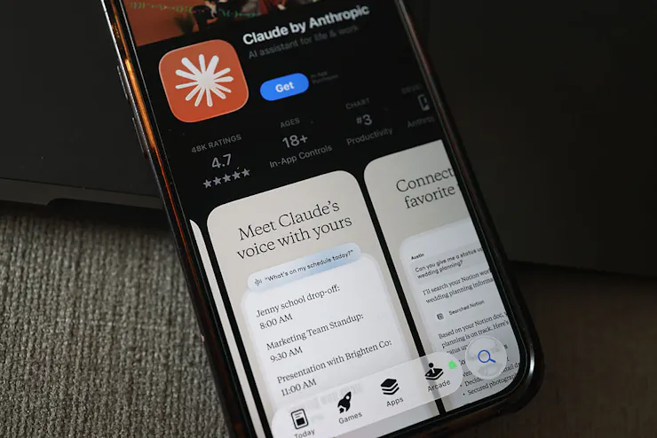 The Claude AI app is seen in the app store on a smartphone with the promotional text 'Meet Claude's voice with yours.'