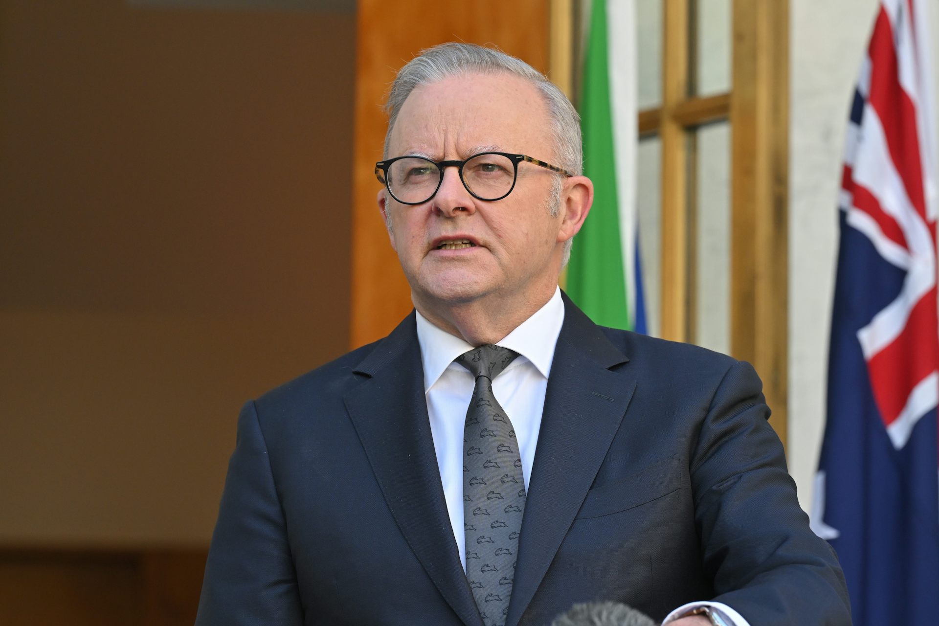 Anthony Albanese speaks at a podium with the Australian flag in the background