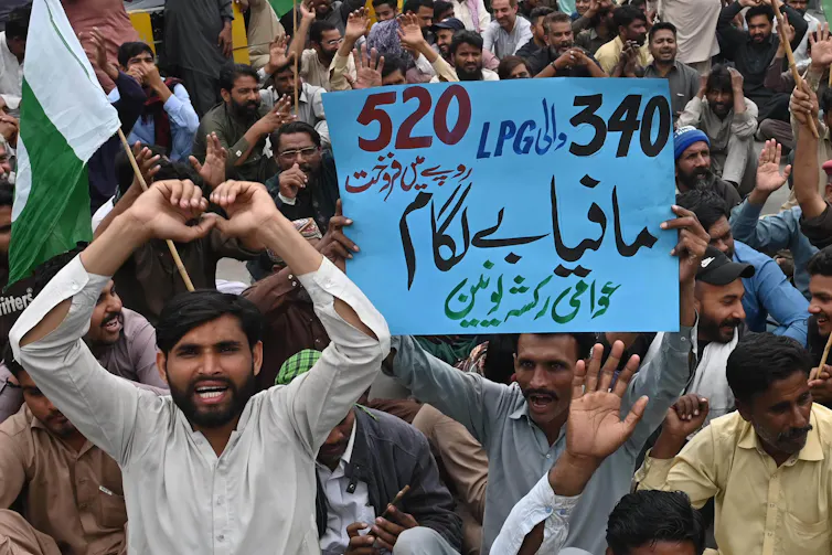 rickshaw driver holding sign protesting rising fuel prices in Pakistan