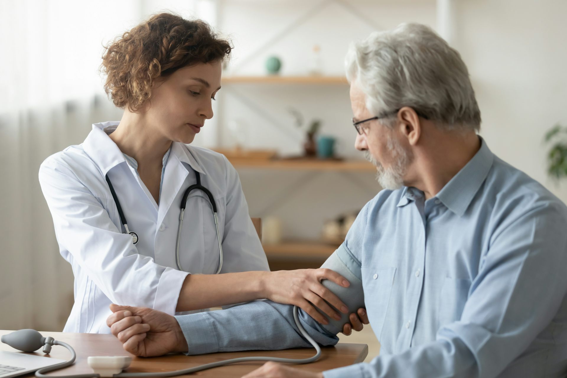 An older man has his blood pressure checked by a young female doctor.