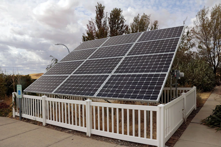 12 solar panels mounted on the ground surrounded by a fence