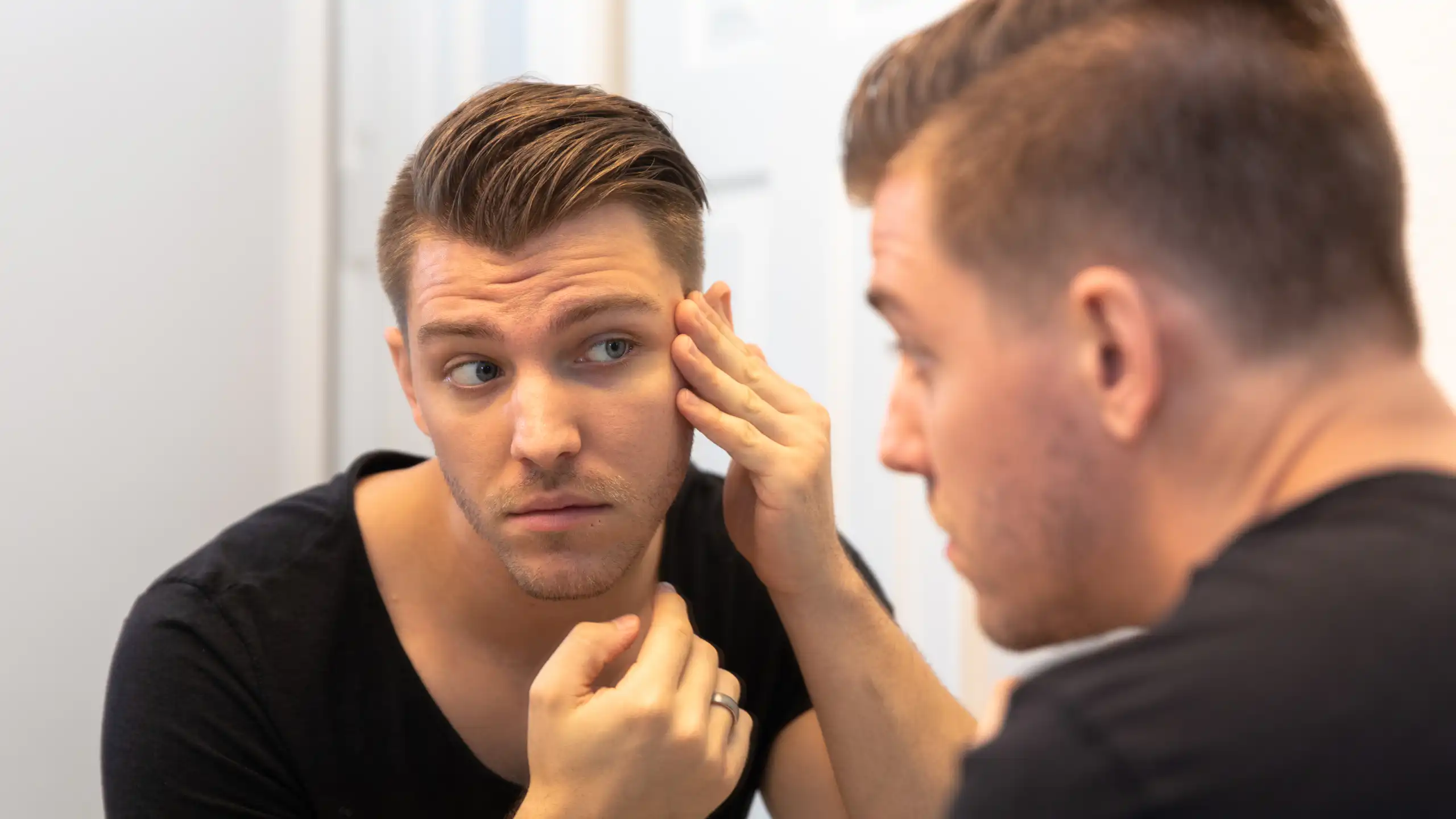 Young man looking at himself in the mirror.