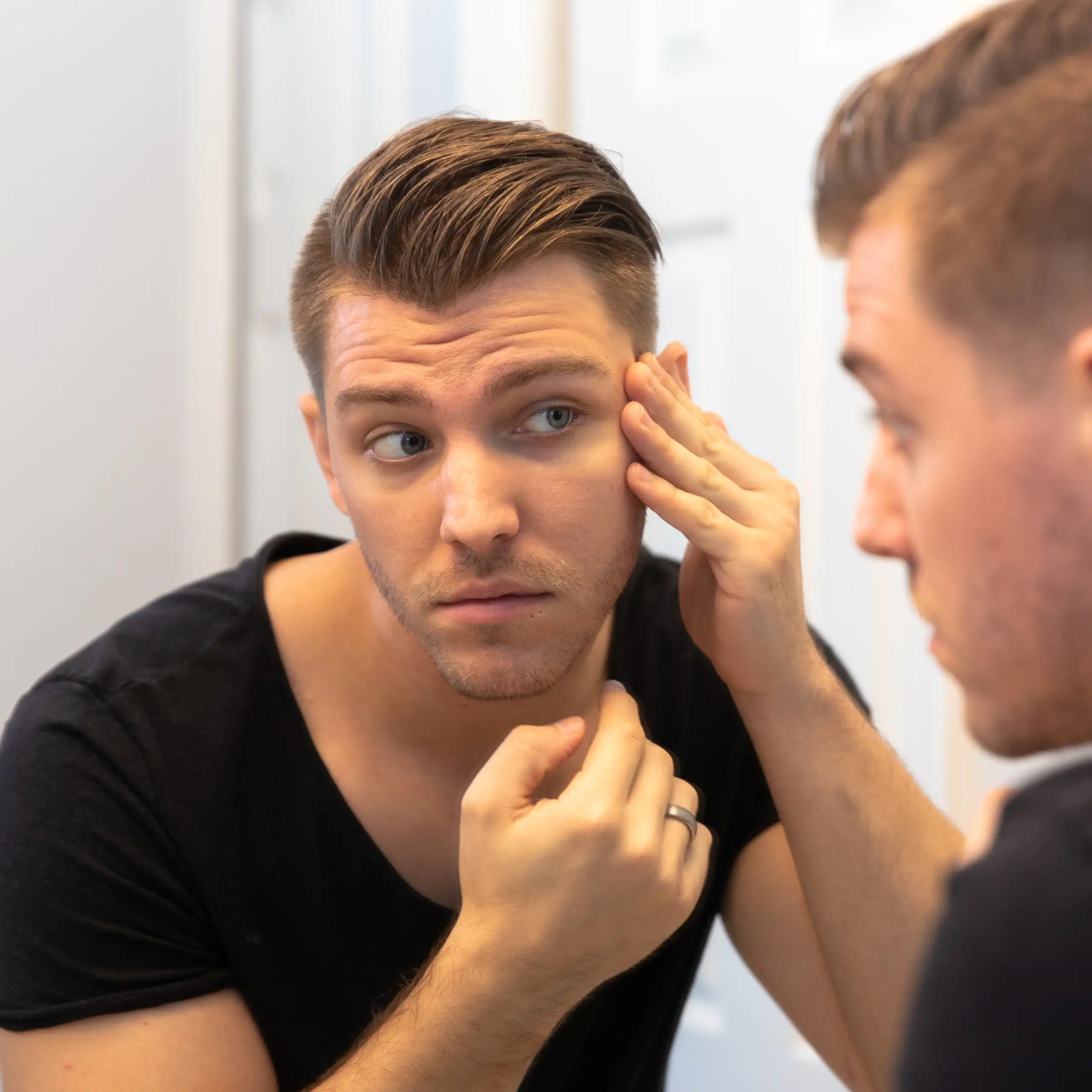 Young man looking at himself in the mirror.
