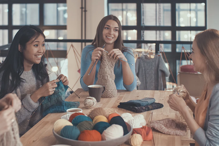 Young women knitting together around a table