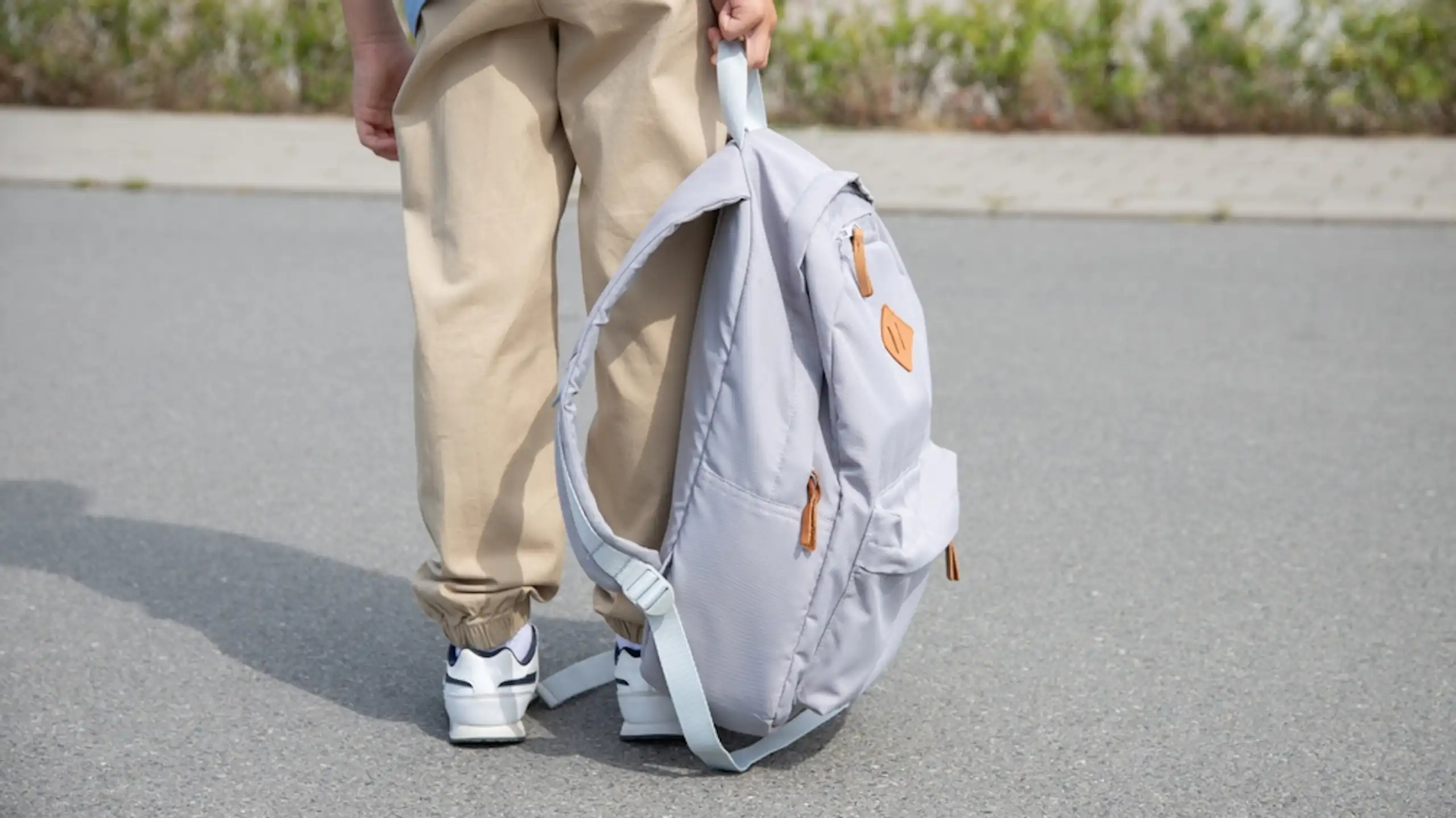 Un enfant qui tient un cartable à la main.