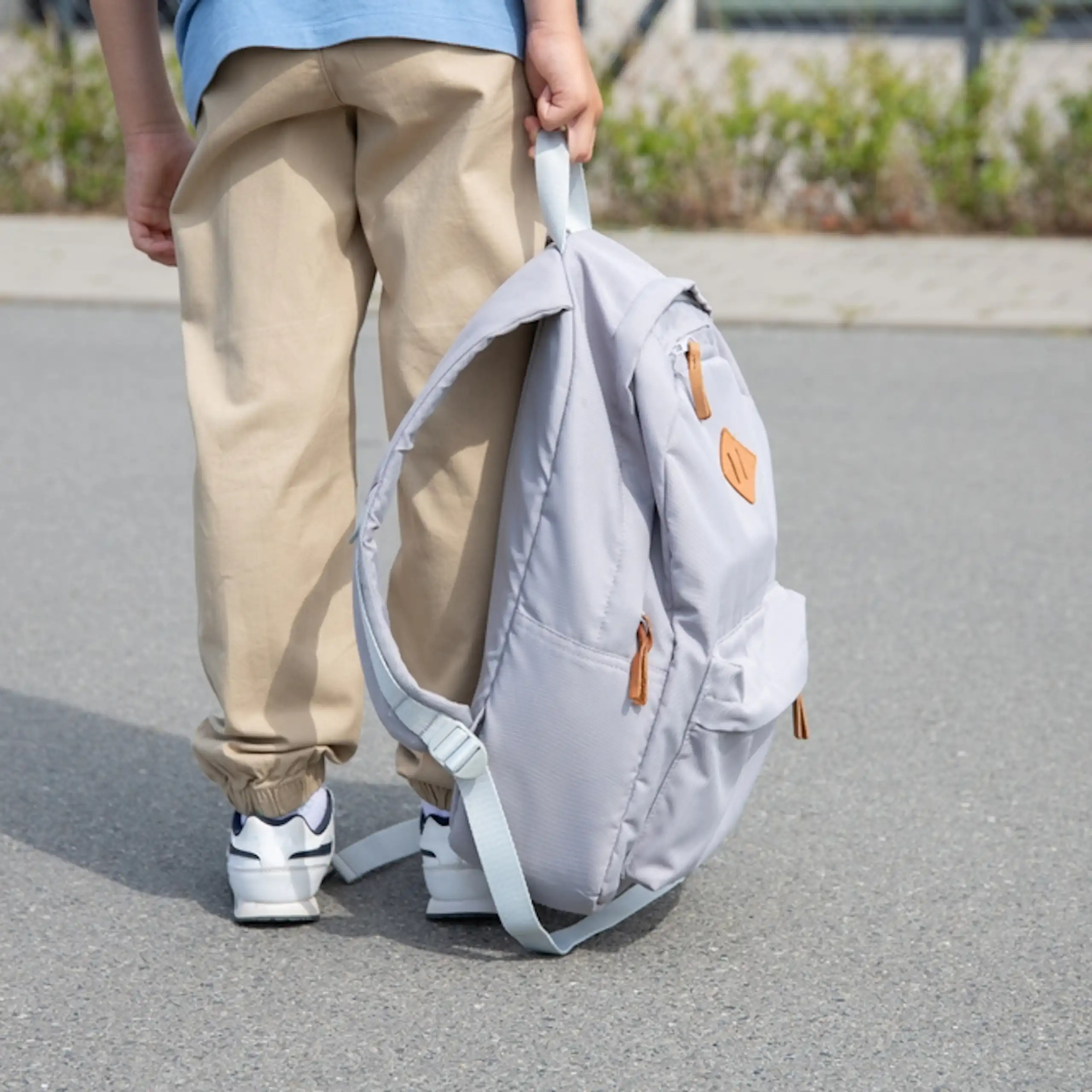 Un enfant qui tient un cartable à la main.