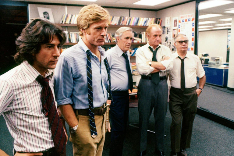 Un grupo de hombres observan algo en un despacho.