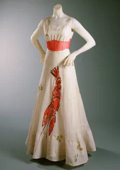 Style Turns into Artwork: a deliciously decadent adventure in the course of the surrealist international of Elsa Schiaparelli 1 A mannequin in a cream sleeveless dress with coral waistband and a lobster stretching down the front.