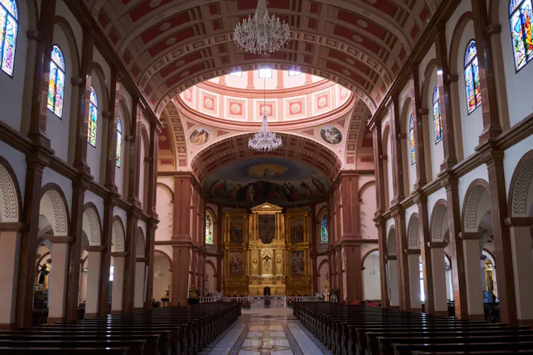 The inside of a large cathedral with arched windows and a dome.