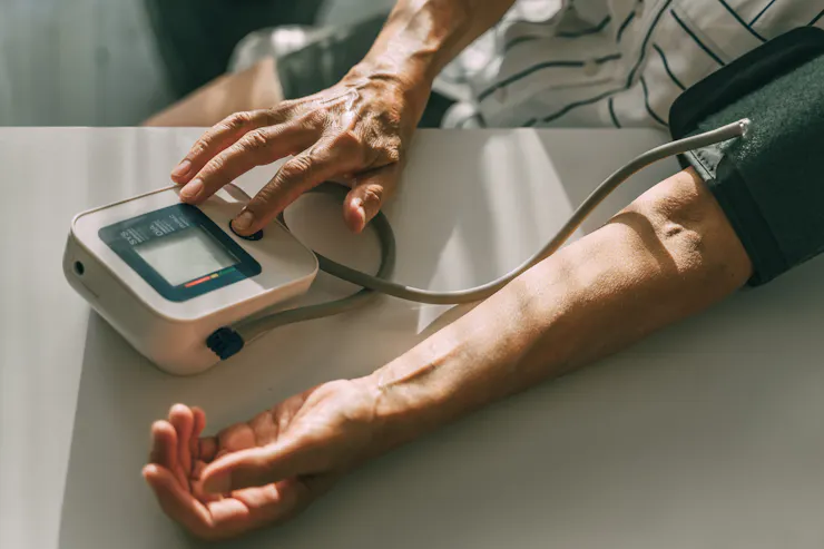 Close-up of arms of person measuring blood pressure with portable monitor