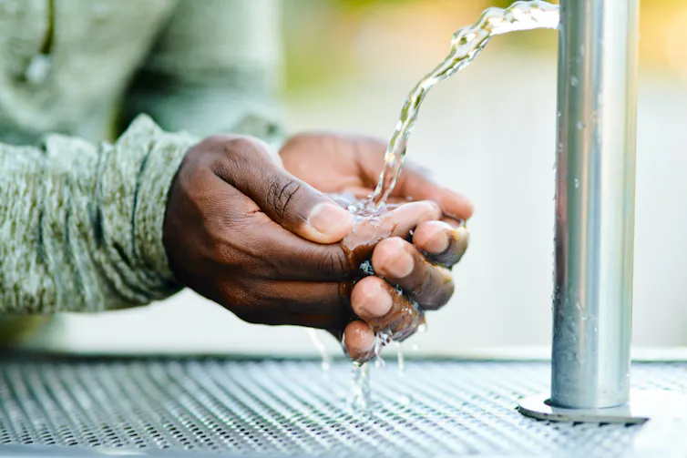 Close-up of cupped hands filling with water from a fountain