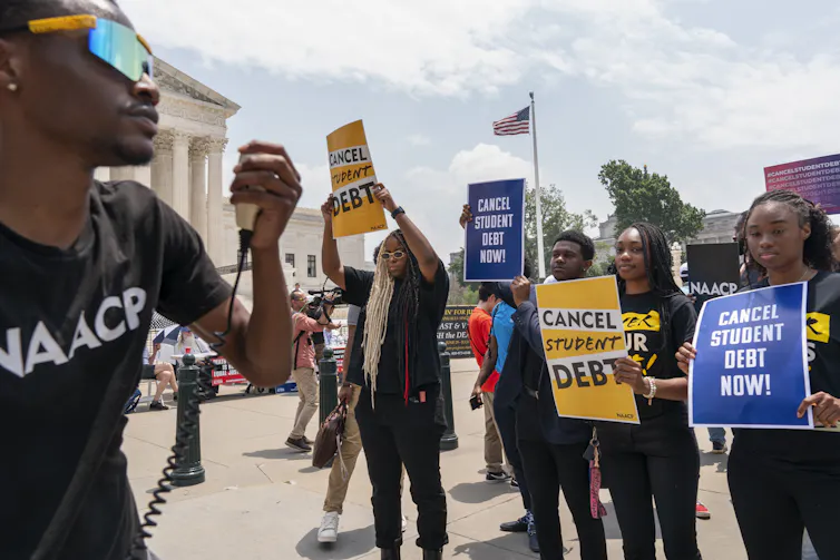 Students seen with signs that say 'cancel student debt.'