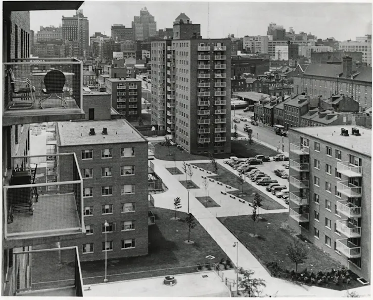 An old black and white photo of large blocks of residential units as far as the eye can see, open walkways between them.