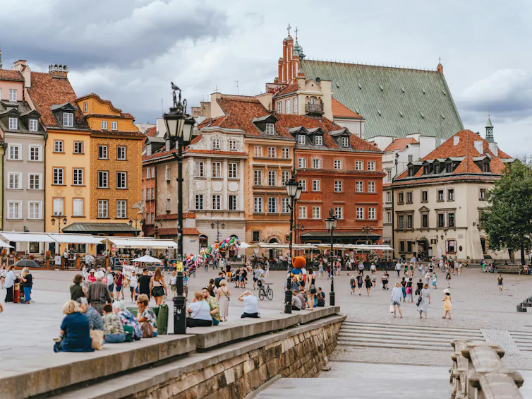 A picturesque city square with old stately buildings and people at a market.