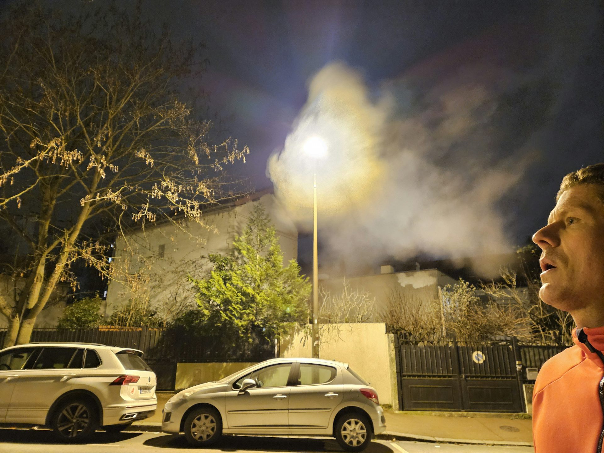 a man blowing in front of a street lamp and creating a cloud of condensation