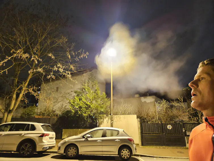 homme soufflant devant un lampadaire et formant un nuage de condensation