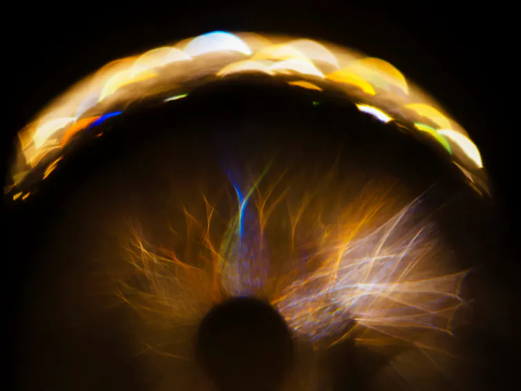 A close-up of the human eye, with a beam of light gathered at the top of the eyeball.