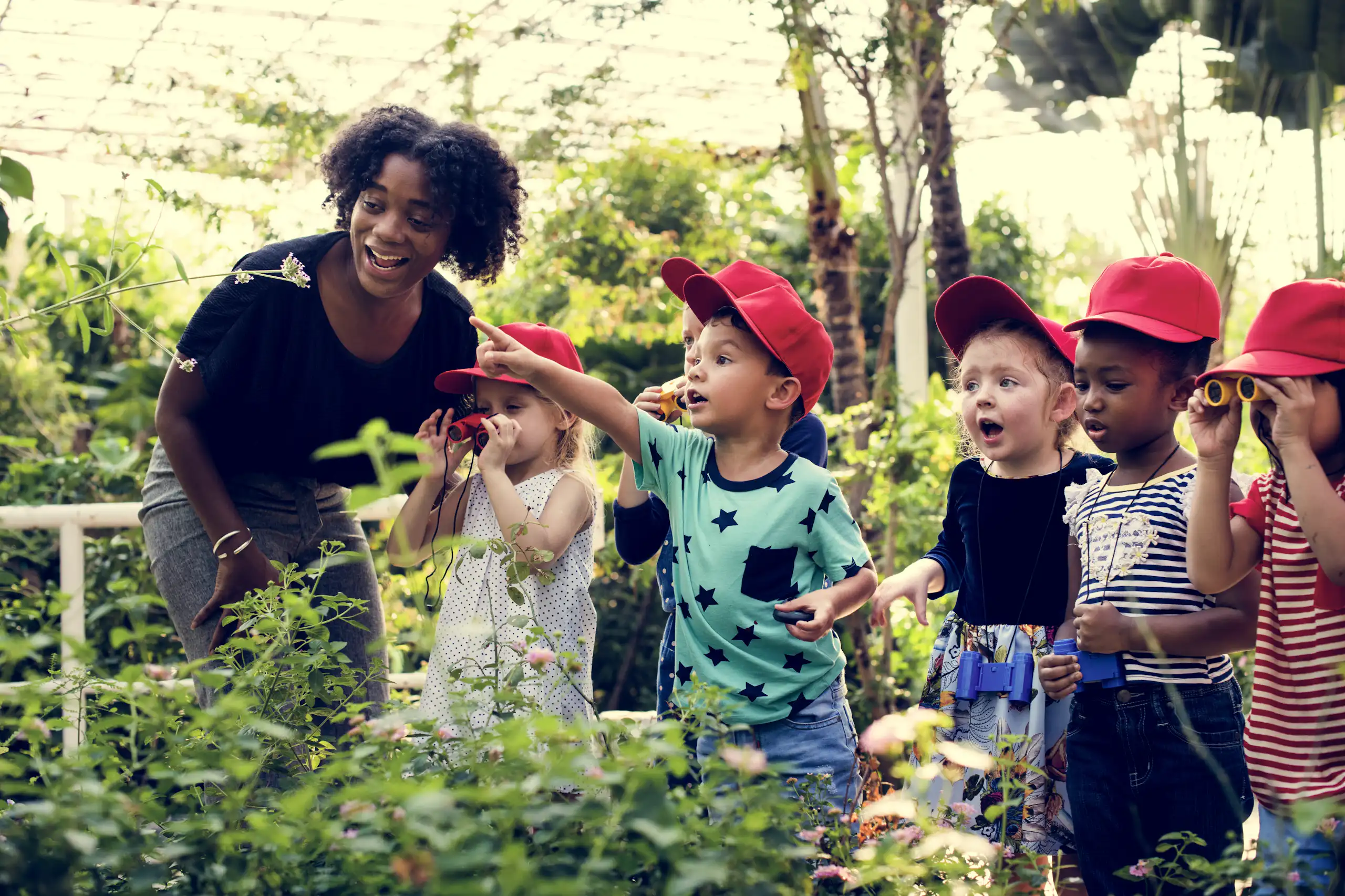 Une enseignante et des enfants dans un jardin.