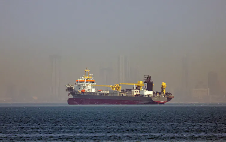 A big vessel at sea with misty city background.