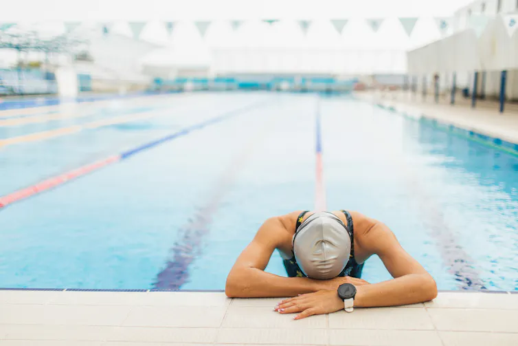 Qué es el coraje, cómo construirlo y por qué hay que arriesgarse 1 Un nadador en el borde de una piscina de carreras con la cabeza gacha.