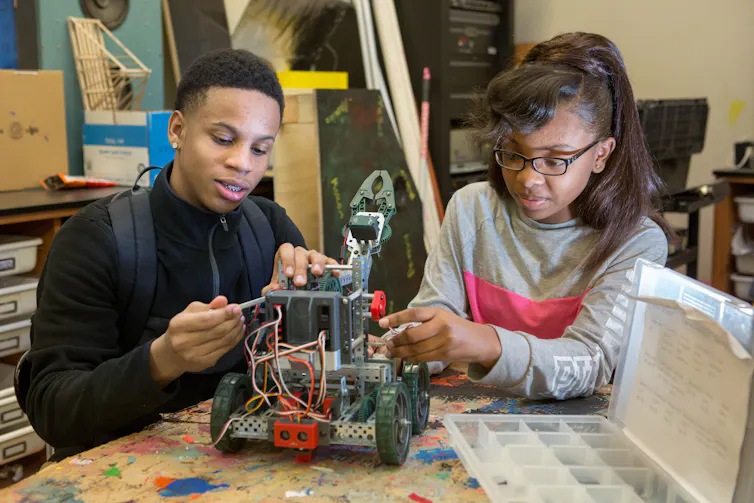 Two students work on robot models.