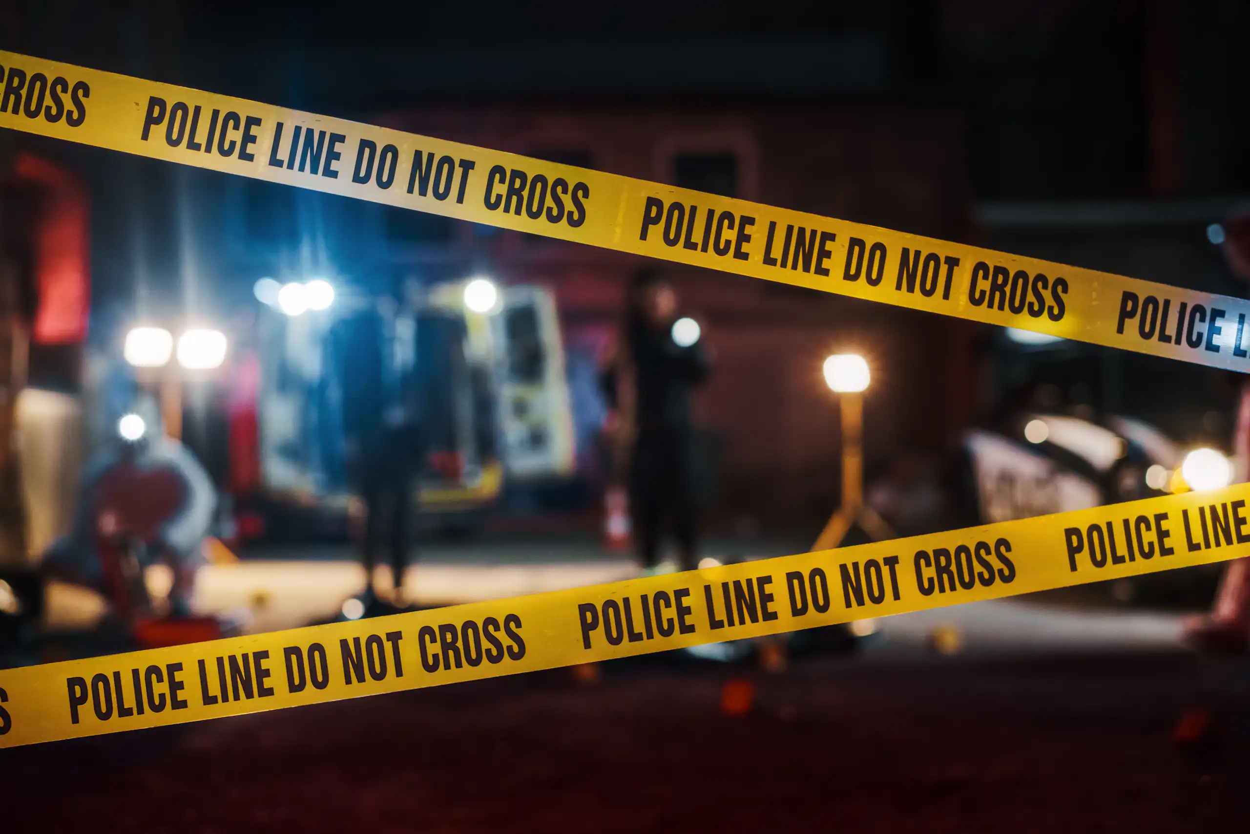 Police tape with a blurred crime scene in the background