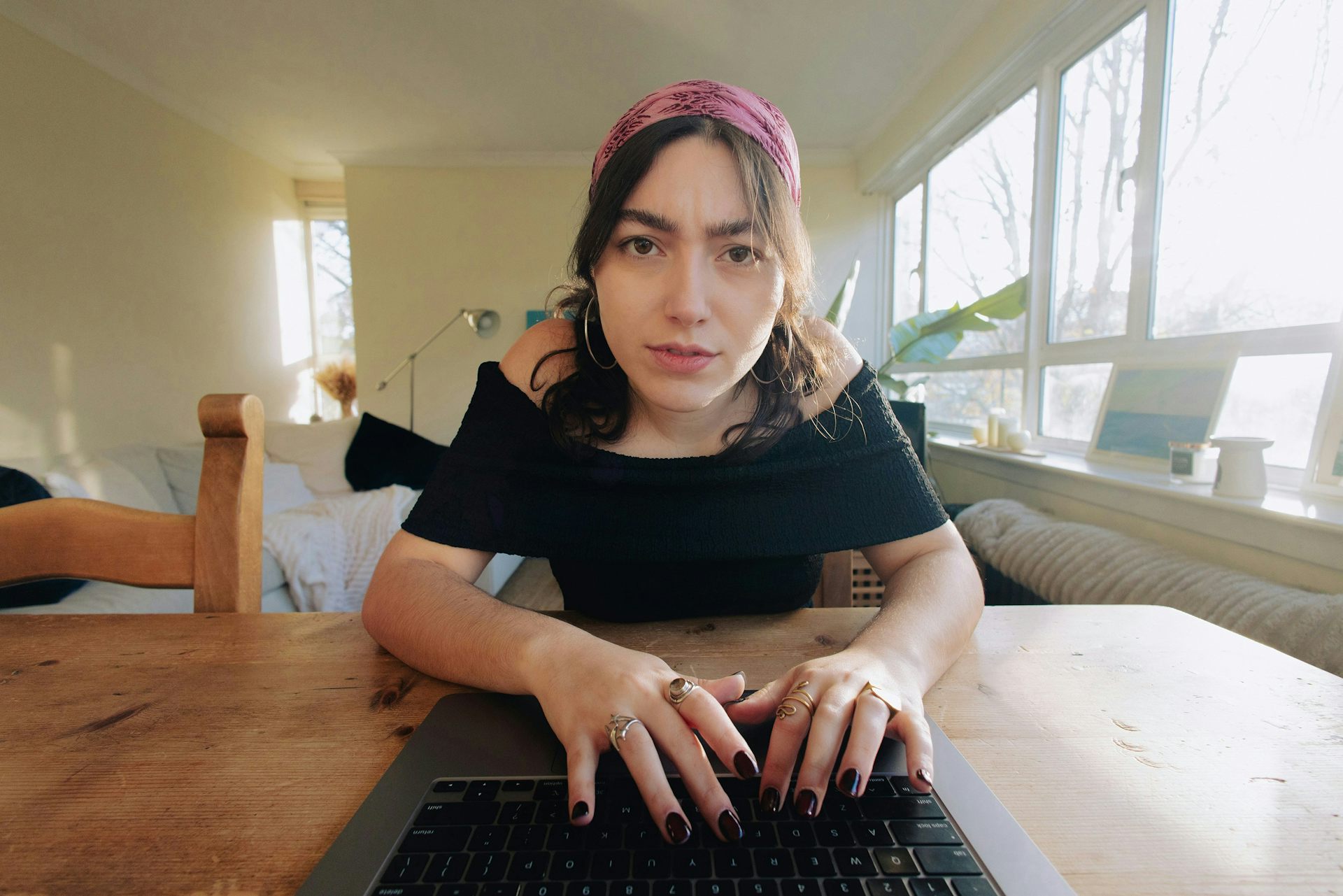 Una mujer frunciendo el ceño ante una computadora portátil.