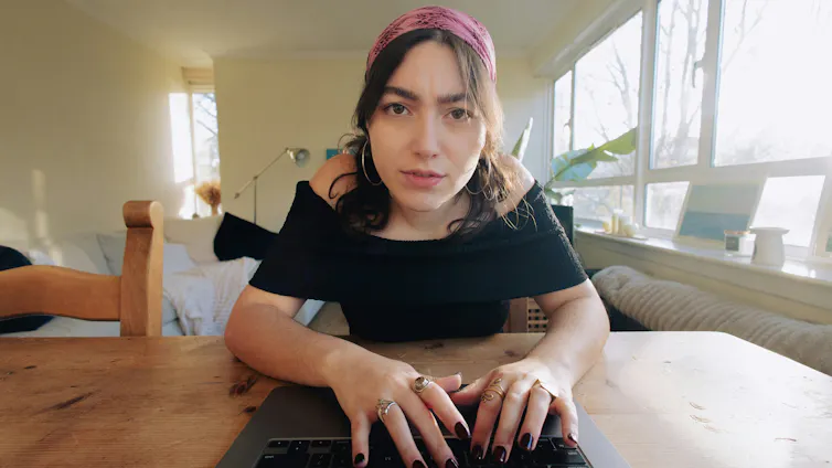 Una mujer frunciendo el ceño ante una computadora portátil.