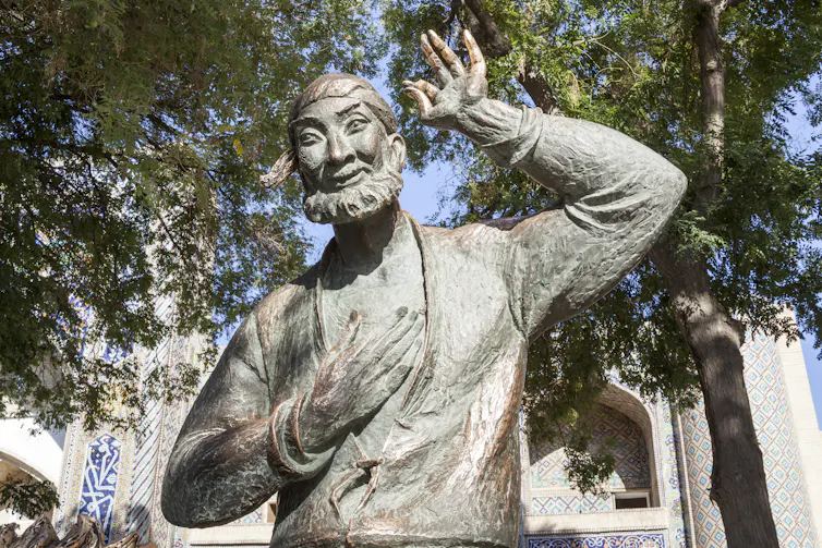 A waist-up statue of a bearded man, seemingly making a comical gesture with his arms raised.