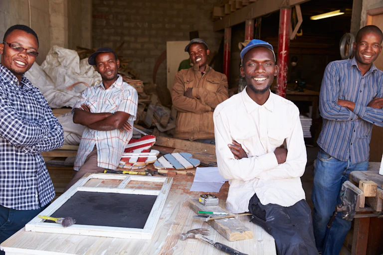 Five men stand around a work table in a workshop