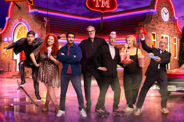 A group of comedians in front of a diner