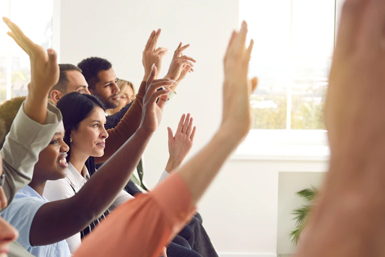 Personas levantando la mano en una sala.