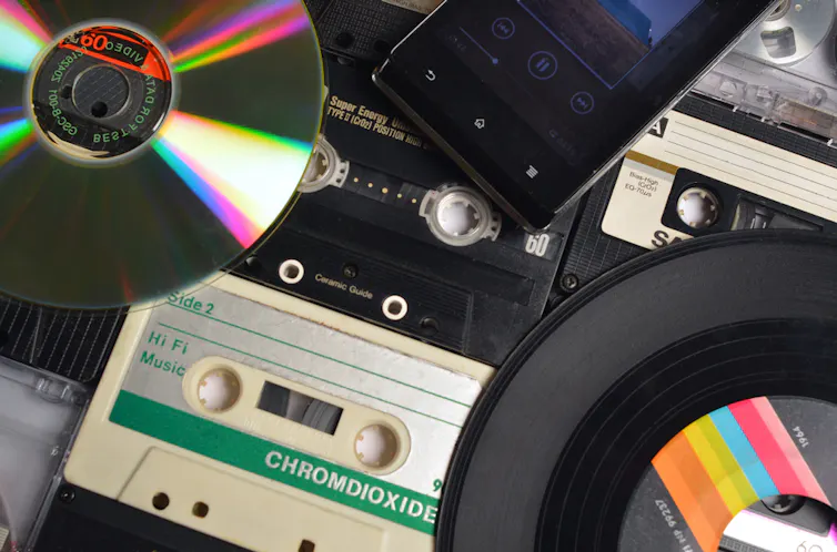 Una imagen en la que se ven un vinilo, una cinta casete, un CD, un MP3...