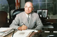 A man in a suit at a desk.