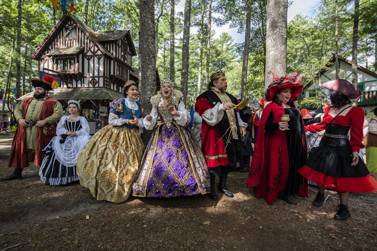 A line of actors dressed in colorful 16th-century garb.