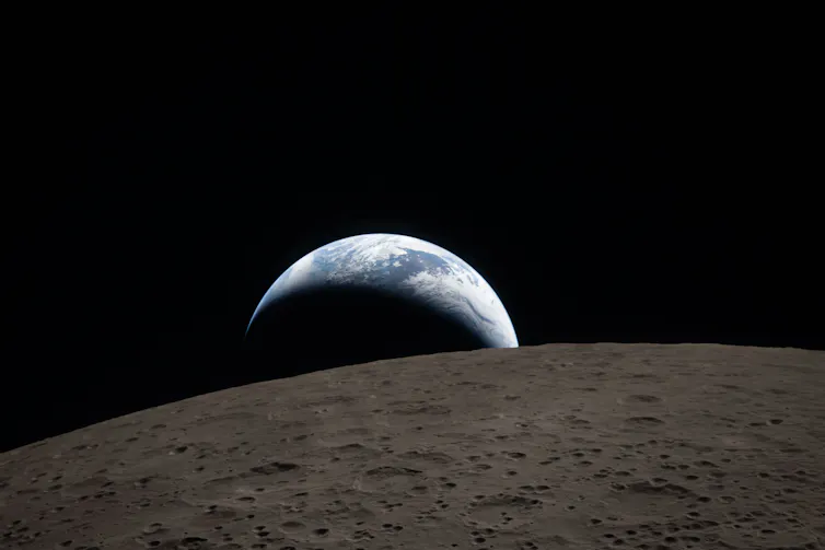 The Earth shown partially shadowed beyond the Moon in space