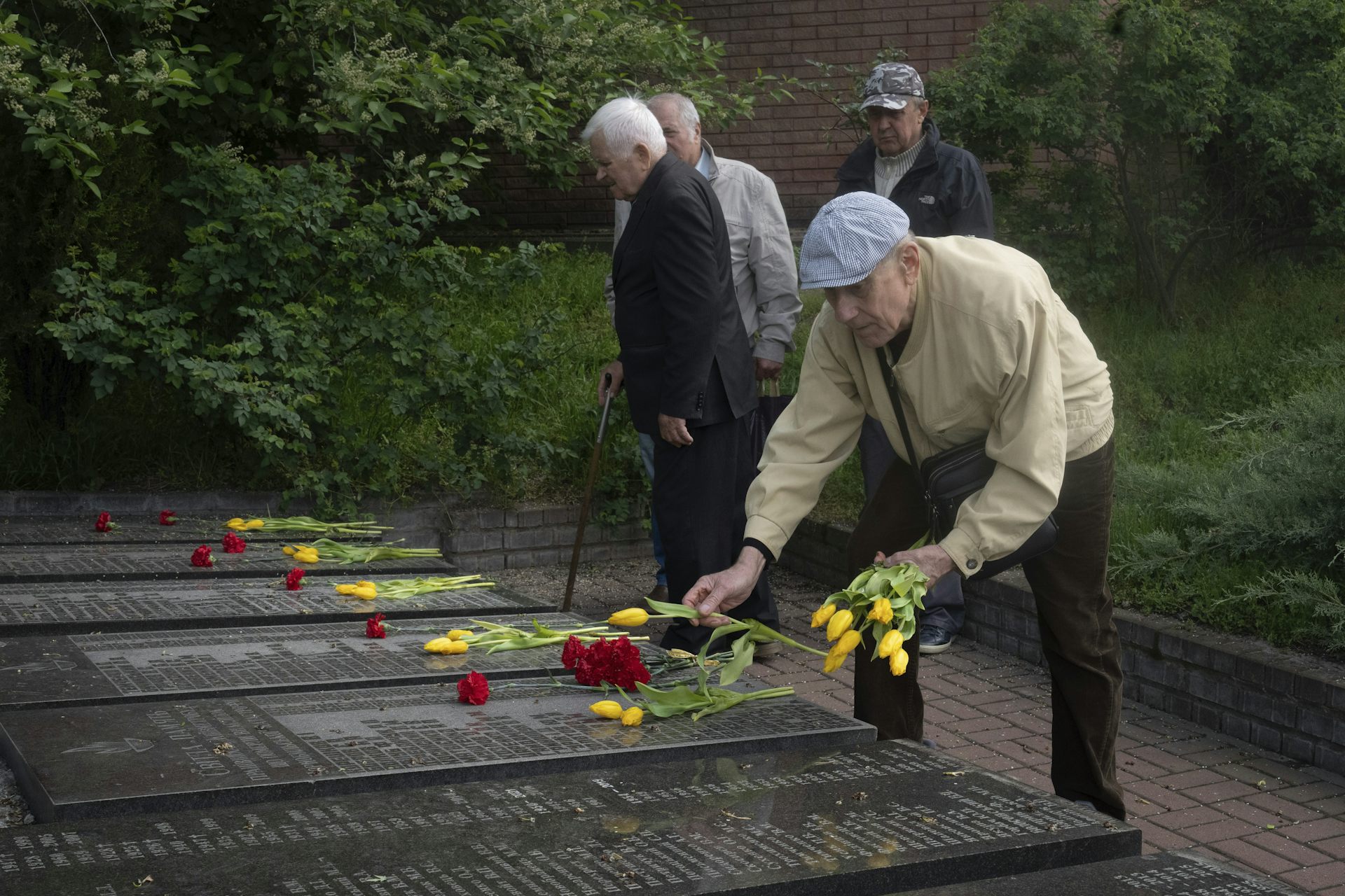 hombres mayores depositan flores en las tumbas
