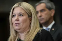 Una mujer de rostro redondo y cabello rubio.