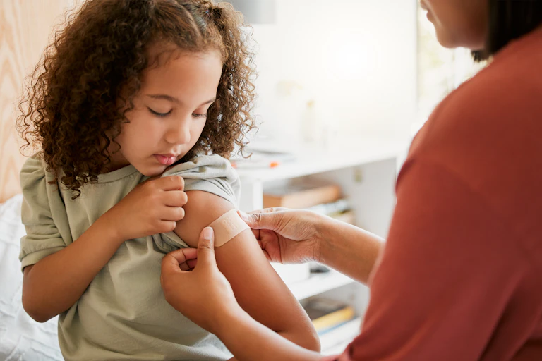 Nurse puts bandaid on child's arm