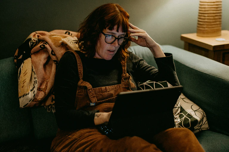 femme lisant sur son ordinateur, l'air choqué