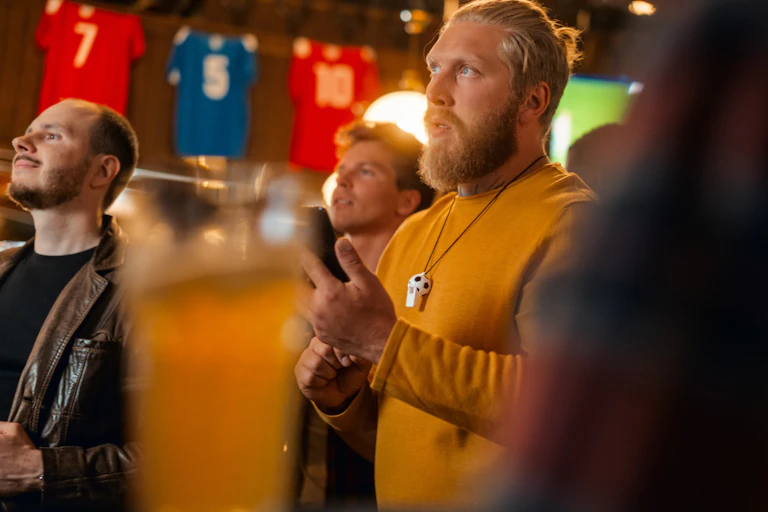 Man in a pub holding his phone concentrating on a screen