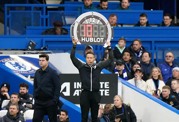 A fourth official displays ten minutes of added time at the end of a Premier League game at Chelsea's Stamford Bridge ground, February 2024.