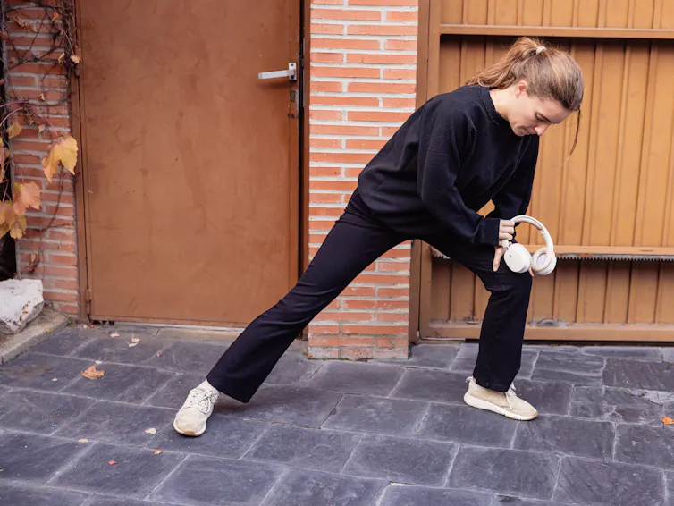 Young woman stretching outside door