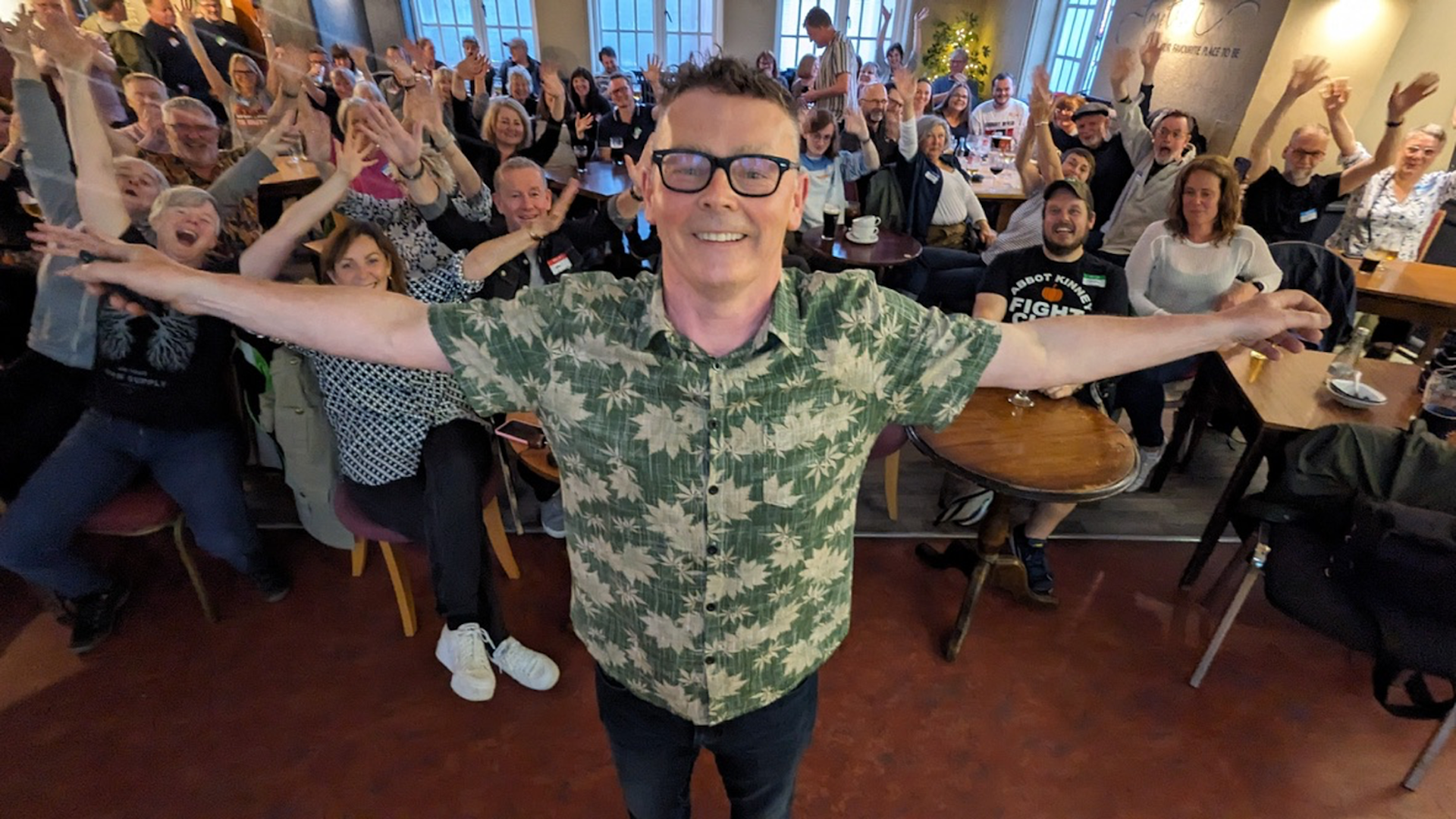 A man standing with arms outstretched in front of a crowd of people