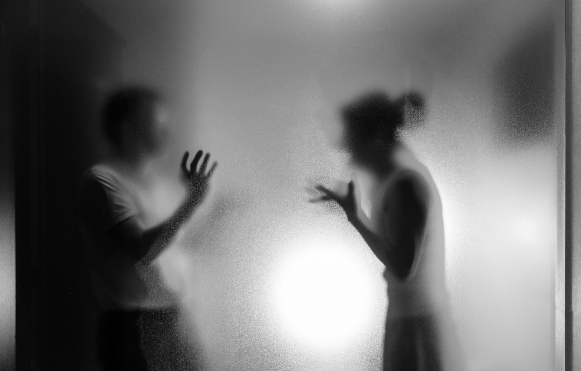 couple arguing behind frosted glass
