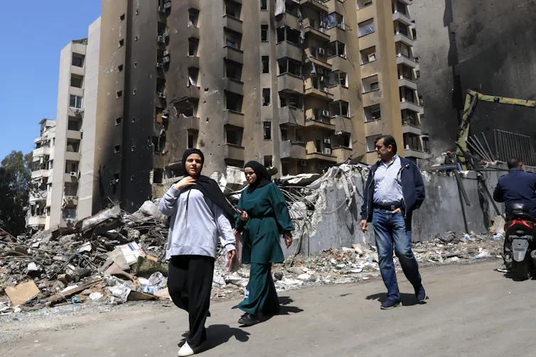 People walk past damaged buildings in the Corniche el-Mazraa area of Beirut.