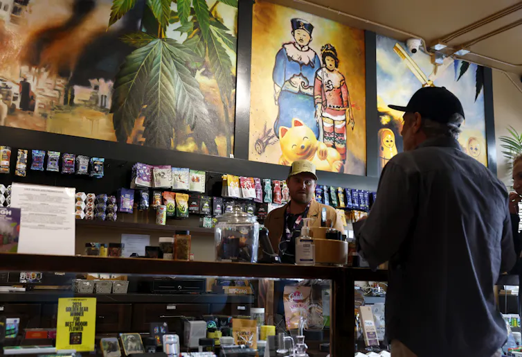 A man in a cannabis store attends to a customer.