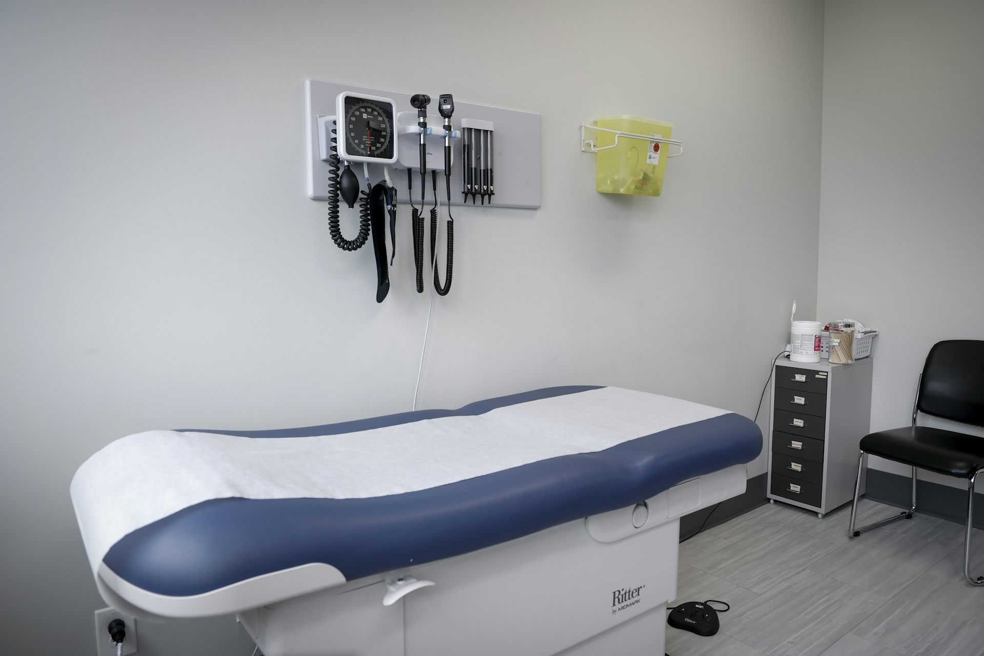 A medical examination room with an examination table and medical tools hanging about it